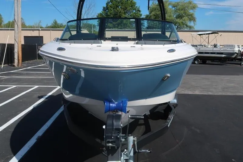 Slide: The Image of 2026 Chaparral 21 SSi boat on trailer outside dealership, blue and white design. - 5