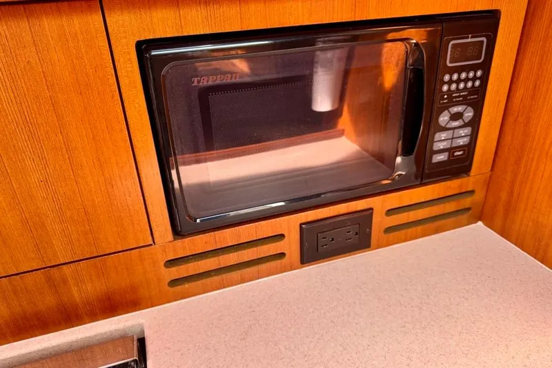 Slide: The Image of Built-in microwave in a 2006 Hunter 38 yacht kitchen, featuring wood paneling and countertop. - 47