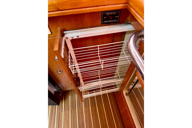 Slide: The Image of Pull-out wire rack in 2006 Hunter 38 yacht kitchen, featuring wood cabinetry and striped flooring. - 48