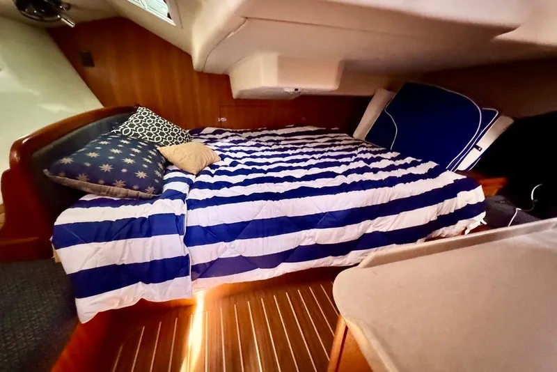 Slide: The Image of Cozy cabin interior of 2006 Hunter 38 sailboat with striped bedding and wooden accents. - 49