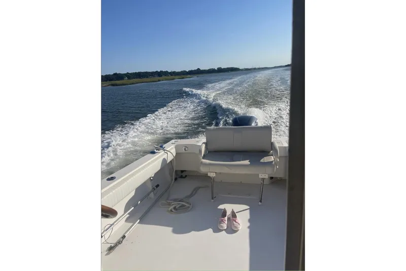 Slide: The Image of 2006 Parker 2520 XL Sport Cabin boat cruising on a sunny day, with shoes on deck. - 4