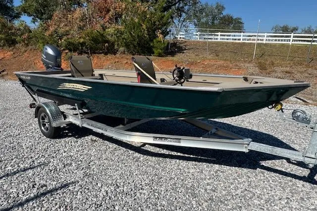 Slide: The Image of 2025 Alweld 1856 PF boat on trailer, parked on gravel, with trees in background. - 13