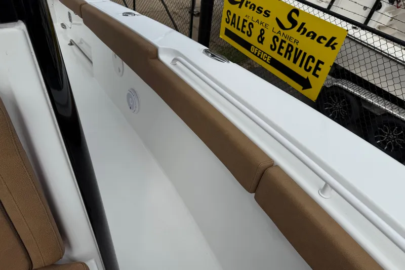 Slide: The Image of 2021 Sea Hunt Gamefish 27 boat interior with brown seating, near sales and service sign. - 21