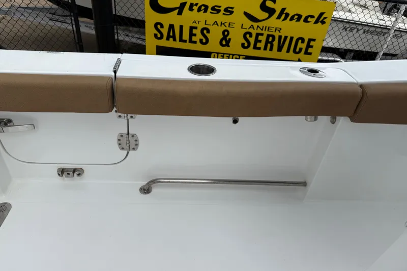 Slide: The Image of 2021 Sea Hunt Gamefish 27 boat interior with tan seating, rod holders, and sales sign. - 52