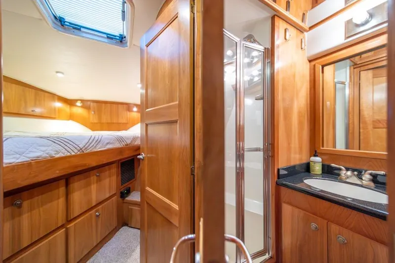 Slide: The Image of Luxurious 2007 Navigator Classic 48 yacht interior with wood finish, featuring a cozy bedroom and bathroom. - 24