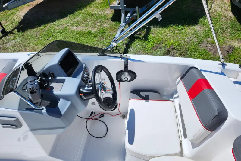 Slide: The Image of 2023 Tahoe T18 boat interior with steering wheel, dashboard, and seating on grass. - 16