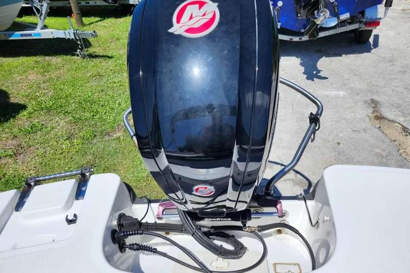 Slide: The Image of 2023 Tahoe T18 boat engine, black with red logo, parked on grass. - 20