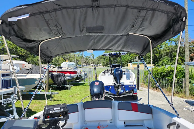 Slide: The Image of 2023 Tahoe T18 boat with canopy, parked outdoors among other boats. - 26