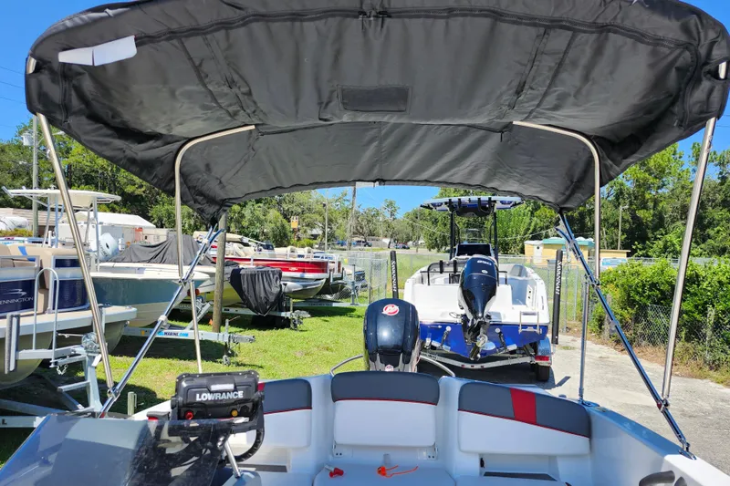 Slide: The Image of 2023 Tahoe T18 boat with canopy, parked outdoors among other boats. - 27
