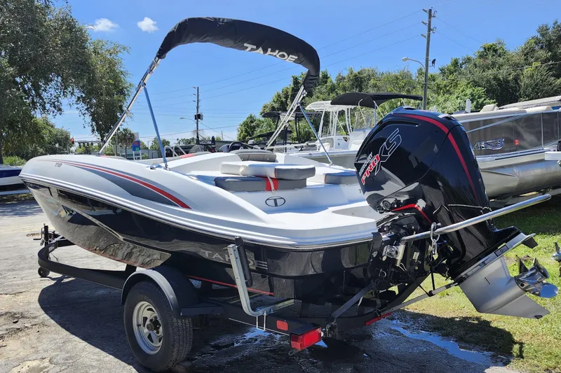 Slide: The Image of 2023 Tahoe T18 boat with outboard motor on a trailer, parked outdoors. - 3