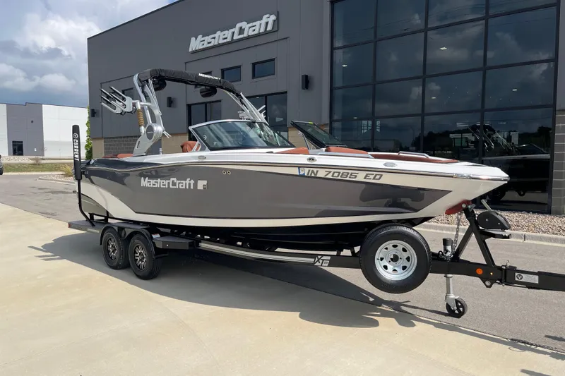 The Image of 2020 MasterCraft XT23 boat on trailer outside dealership building. - 1