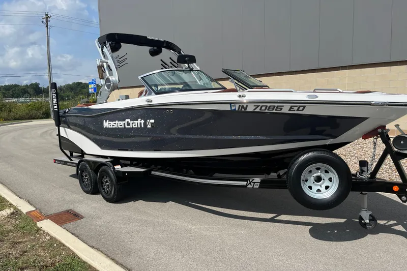 Slide: The Image of 2020 MasterCraft XT23 boat on trailer, parked outdoors, side view. - 16