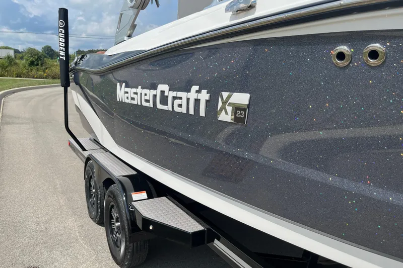 Slide: The Image of 2020 MasterCraft XT23 boat on trailer, glittery finish, parked on road. - 17