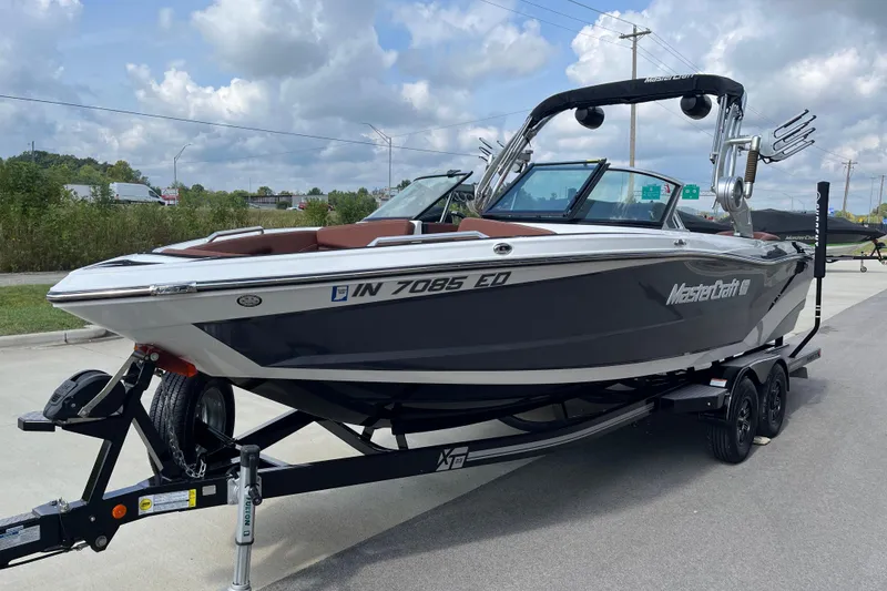 Slide: The Image of 2020 MasterCraft XT23 boat on trailer, parked on a road under a cloudy sky. - 4