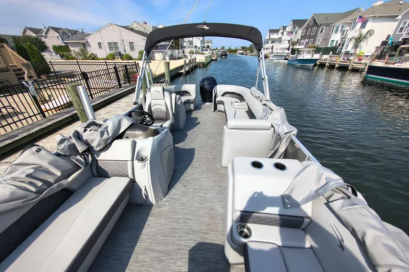 Slide: The Image of 2023 Bennington 25 LSRC pontoon boat docked in a scenic canal setting. - 9