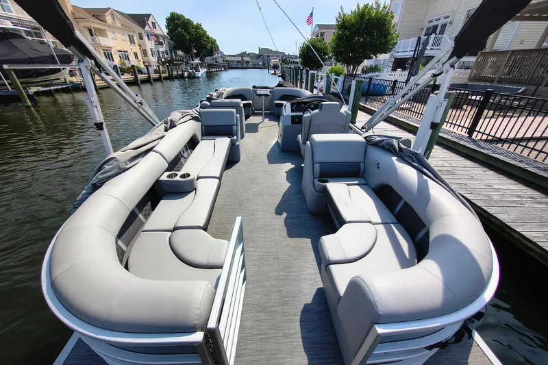 Slide: The Image of 2023 Bennington 25 LSRC pontoon boat with spacious seating, docked in a scenic marina. - 3
