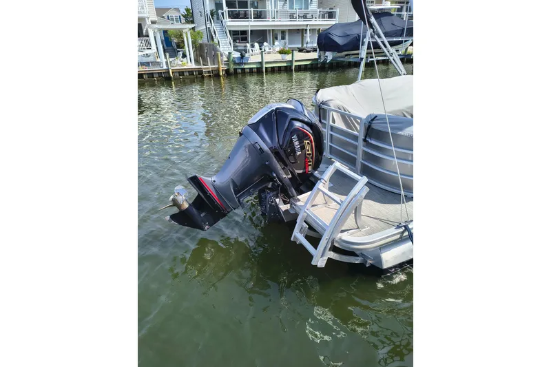Slide: The Image of 2023 Bennington 25 LSRC pontoon boat with Yamaha outboard motor docked by waterfront homes. - 15