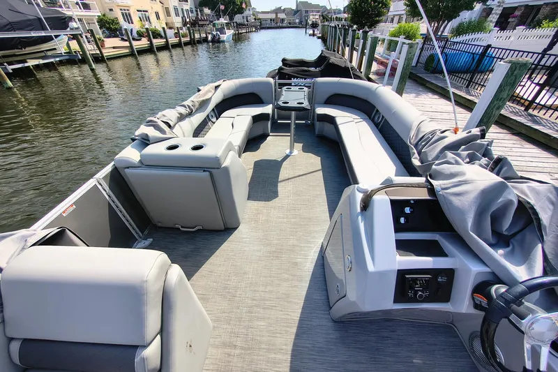 Slide: The Image of 2023 Bennington 25 LSRC pontoon boat with spacious seating, docked by a canal. - 12