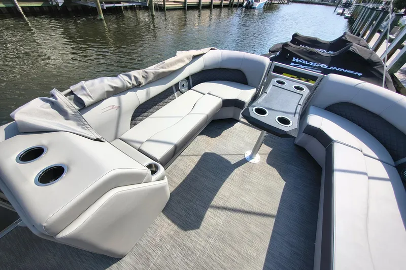 Slide: The Image of Luxurious seating on 2023 Bennington 25 LSRC pontoon boat with cup holders, docked by water. - 10
