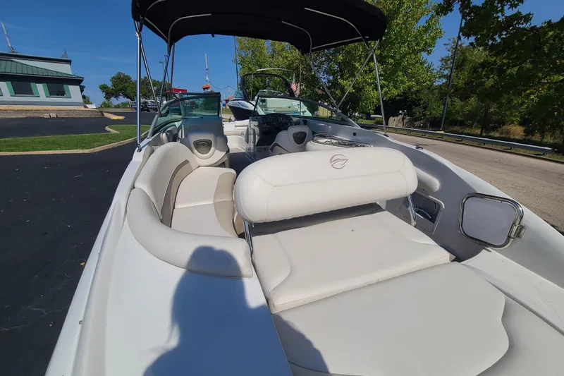 Slide: The Image of 2007 Crownline 252 EX boat with white seating and canopy, parked outdoors. - 4
