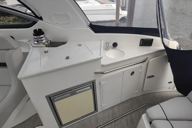 Slide: The Image of 2017 Rinker EX 320 boat interior with kitchenette and seating area. - 17