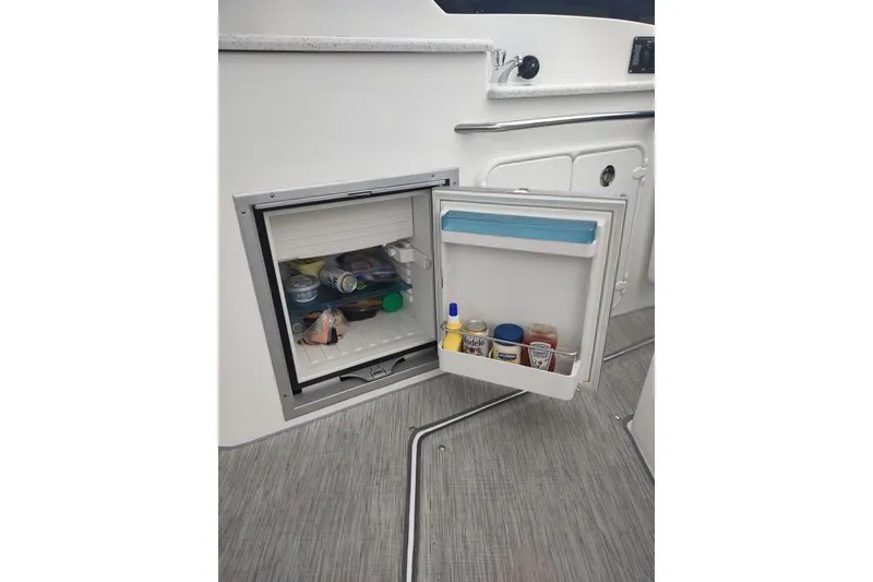 Slide: The Image of Open mini fridge on 2017 Rinker EX 320 boat, stocked with beverages and condiments. - 18