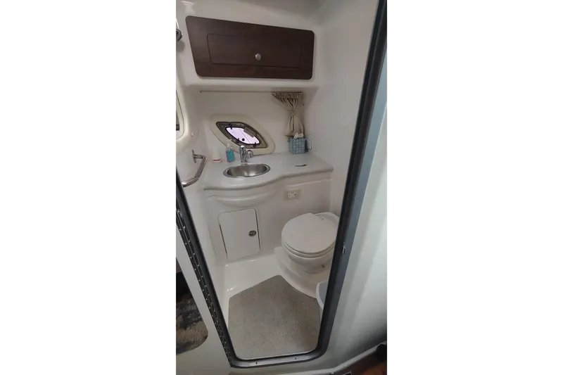Slide: The Image of 2017 Rinker EX 320 boat bathroom with sink, toilet, and storage cabinet. - 32