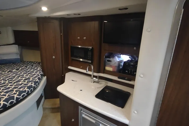 Slide: The Image of 2017 Rinker EX 320 cabin interior with kitchenette and bed. - 38