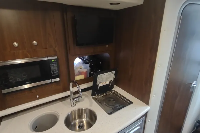 Slide: The Image of 2017 Rinker EX 320 yacht kitchenette with sink, microwave, and stove. - 40
