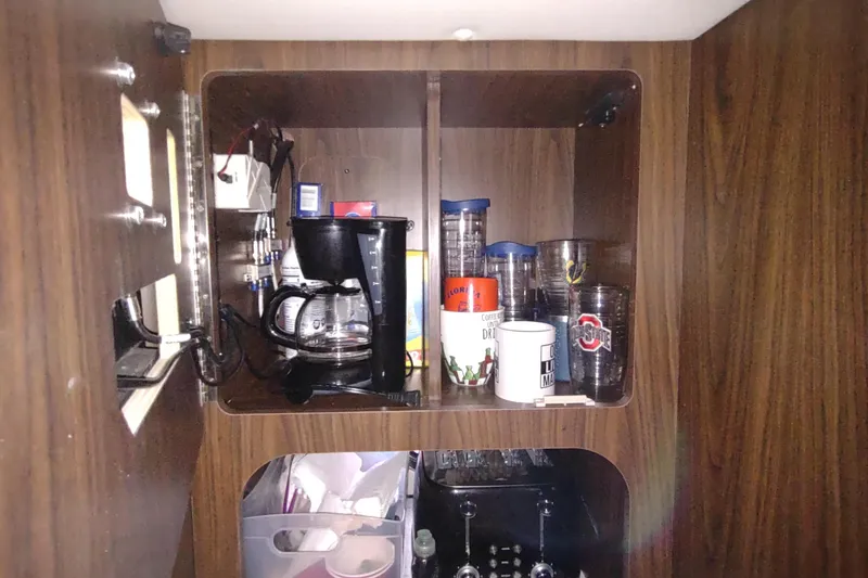 Slide: The Image of Cabinet interior with coffee maker and mugs on a 2017 Rinker EX 320 boat. - 41