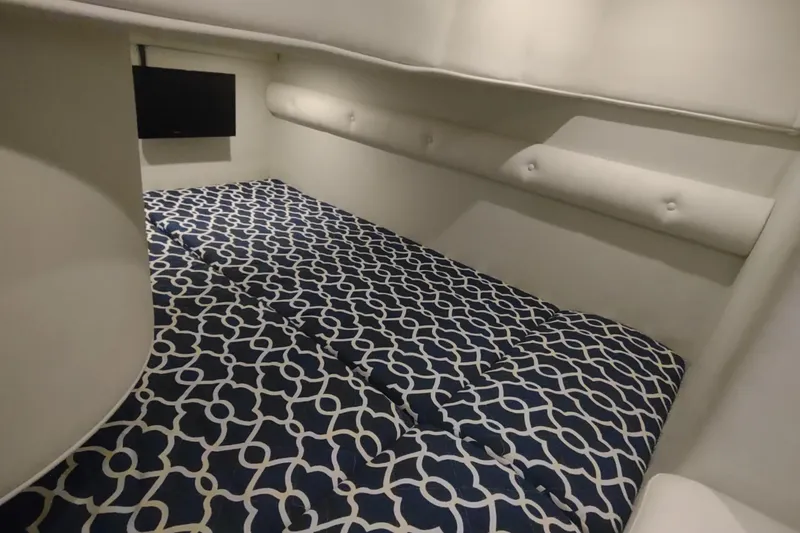 Slide: The Image of 2017 Rinker EX 320 cabin interior with patterned bedding and wall-mounted TV. - 43