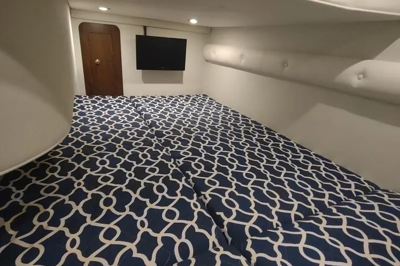 Slide: The Image of 2017 Rinker EX 320 cabin interior with patterned bedding and wall-mounted TV. - 44