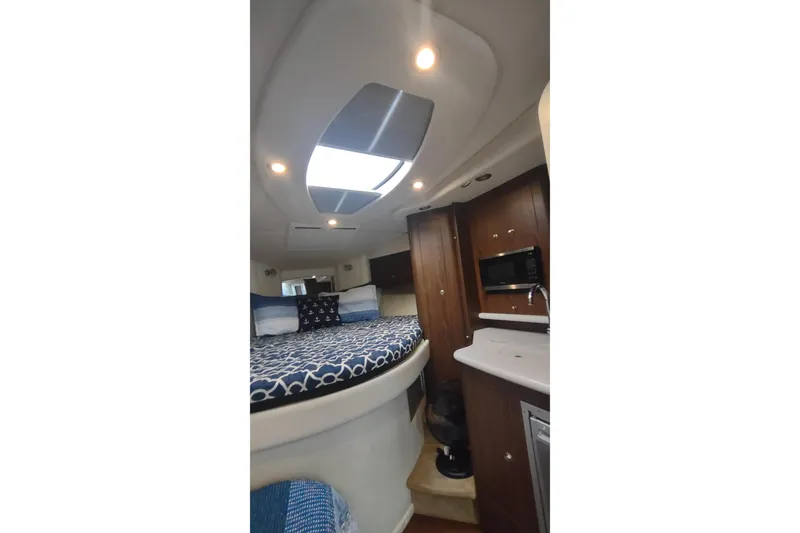 Slide: The Image of 2017 Rinker EX 320 cabin interior with bed, skylight, and kitchenette. - 45