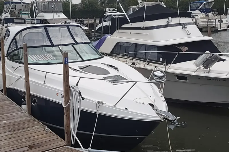 The Image of 2017 Rinker EX 320 boat docked at a marina, surrounded by other vessels. - 9