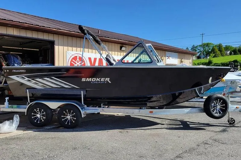 Slide: The Image of 2025 Smoker Craft Phantom 20 X2 OS boat on trailer, parked outside a building. - 2