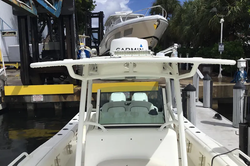 Slide: The Image of 2016 Mako 284 Center Console boat docked at marina with lush greenery. - 14