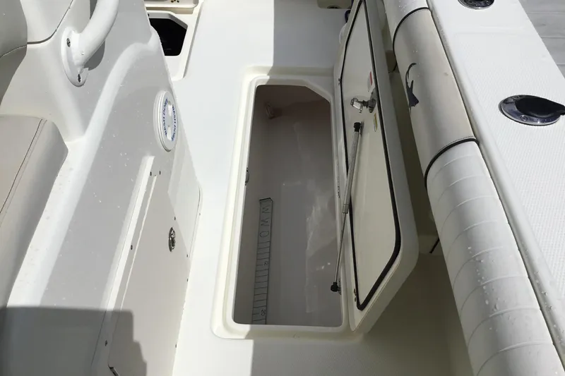 Slide: The Image of 2016 Mako 284 Center Console boat storage compartment with open hatch and seating area. - 30
