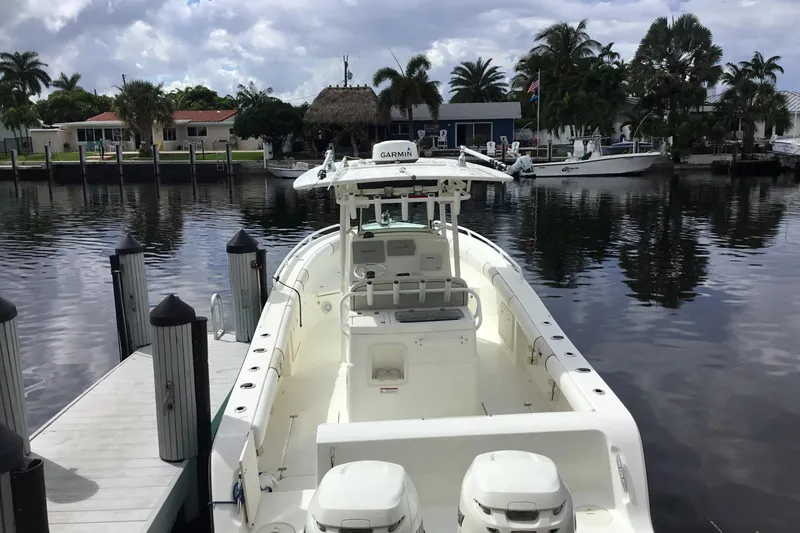 Slide: The Image of 2016 Mako 284 Center Console boat docked by a scenic waterfront. - 62