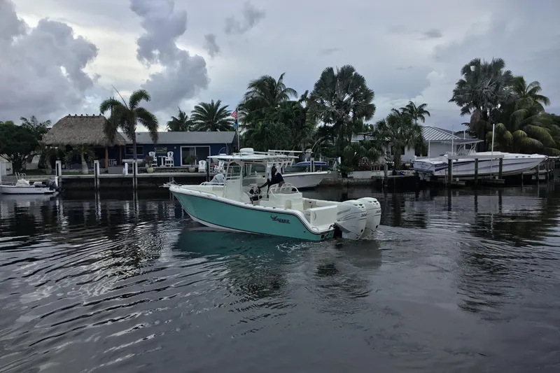 Slide: The Image of 2016 Mako 284 Center Console boat on calm water near a tropical dock. - 67