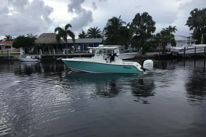 Slide: The Image of 2016 Mako 284 Center Console boat cruising on a calm waterway with palm trees. - 68