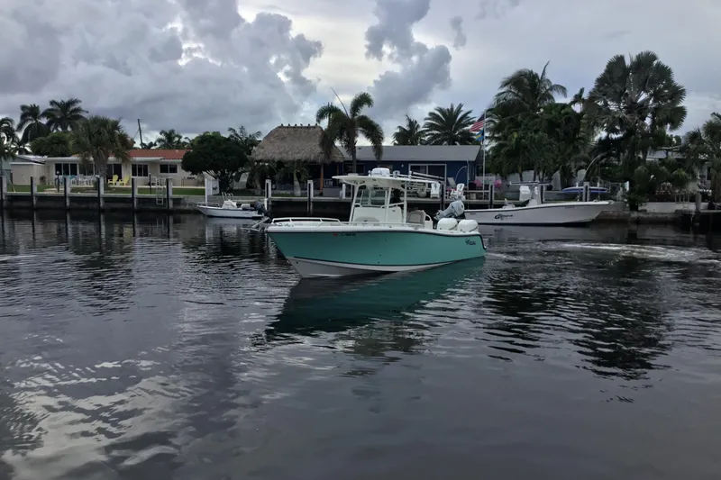 Slide: The Image of 2016 Mako 284 Center Console boat cruising on a calm waterfront with palm trees. - 69