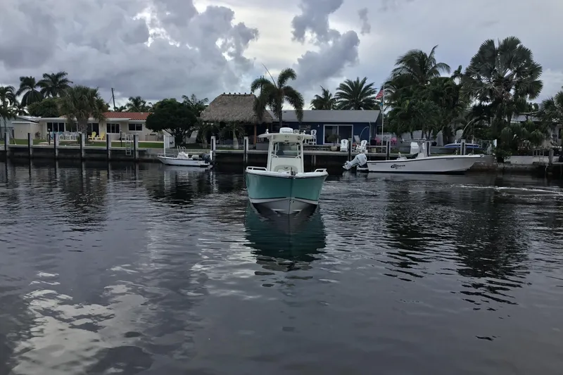 Slide: The Image of 2016 Mako 284 Center Console boat on calm water near a residential dock. - 70