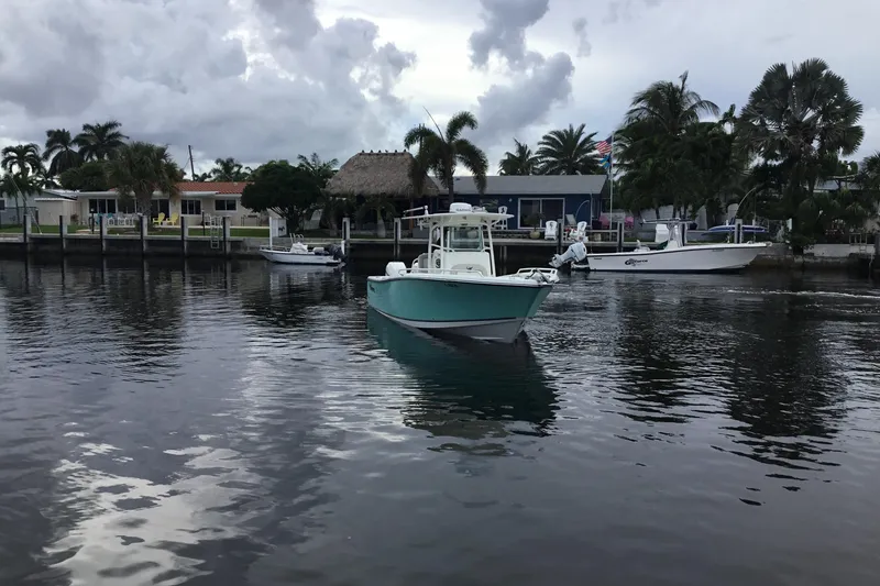 Slide: The Image of 2016 Mako 284 Center Console boat on a calm waterfront with palm trees. - 71