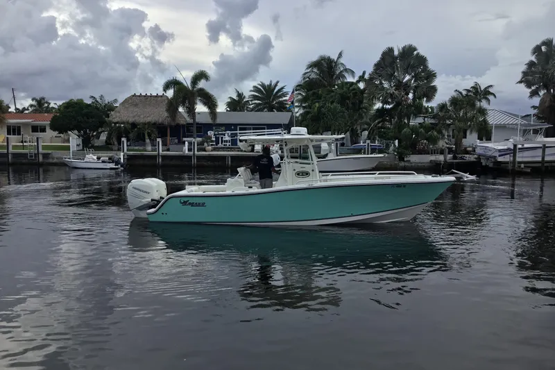 Slide: The Image of 2016 Mako 284 Center Console boat on calm water near a marina. - 74