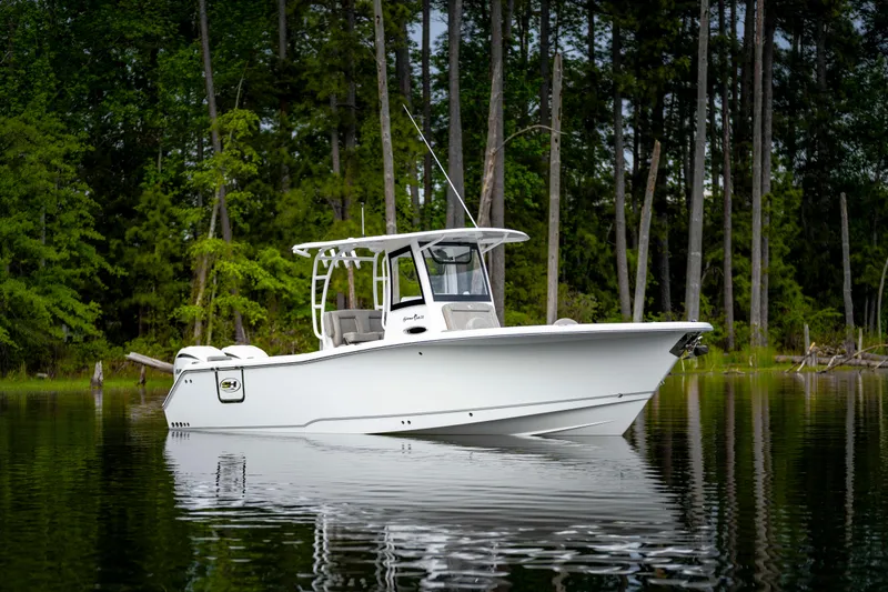 Slide: The Image of 2026 Sea Hunt Gamefish 28 boat on calm water, surrounded by lush forest. - 19