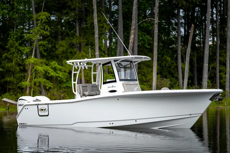 Slide: The Image of 2026 Sea Hunt Gamefish 28 Forward Seating boat on calm water, surrounded by trees. - 20
