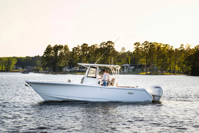 Slide: The Image of 2026 Sea Hunt Gamefish 28 boat on a serene lake with forested shoreline. - 5