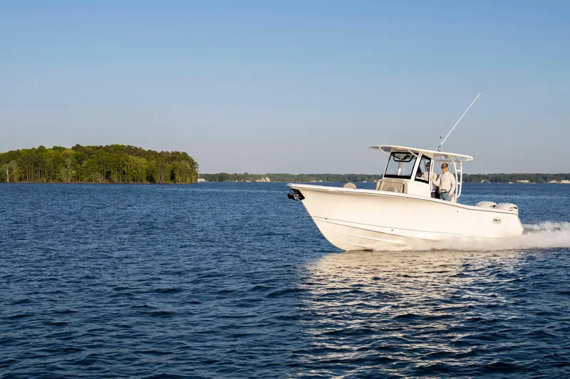 Slide: The Image of 2026 Sea Hunt Gamefish 28 cruising on a serene lake with forested shoreline. - 8
