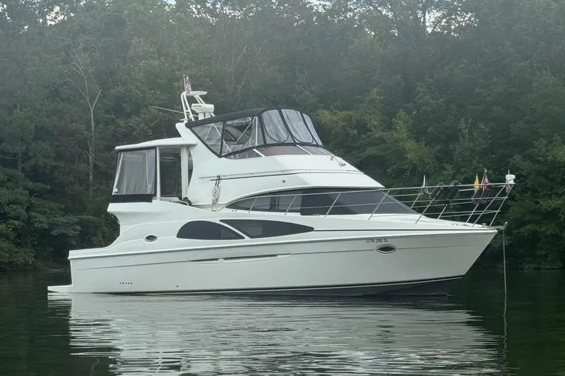 The Image of 2005 Carver 41 Cockpit Motor Yacht on calm water, surrounded by lush greenery. - 0