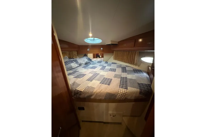 Slide: The Image of 2005 Carver 41 Cockpit Motor Yacht bedroom with quilted bedspread and wooden cabinetry. - 10